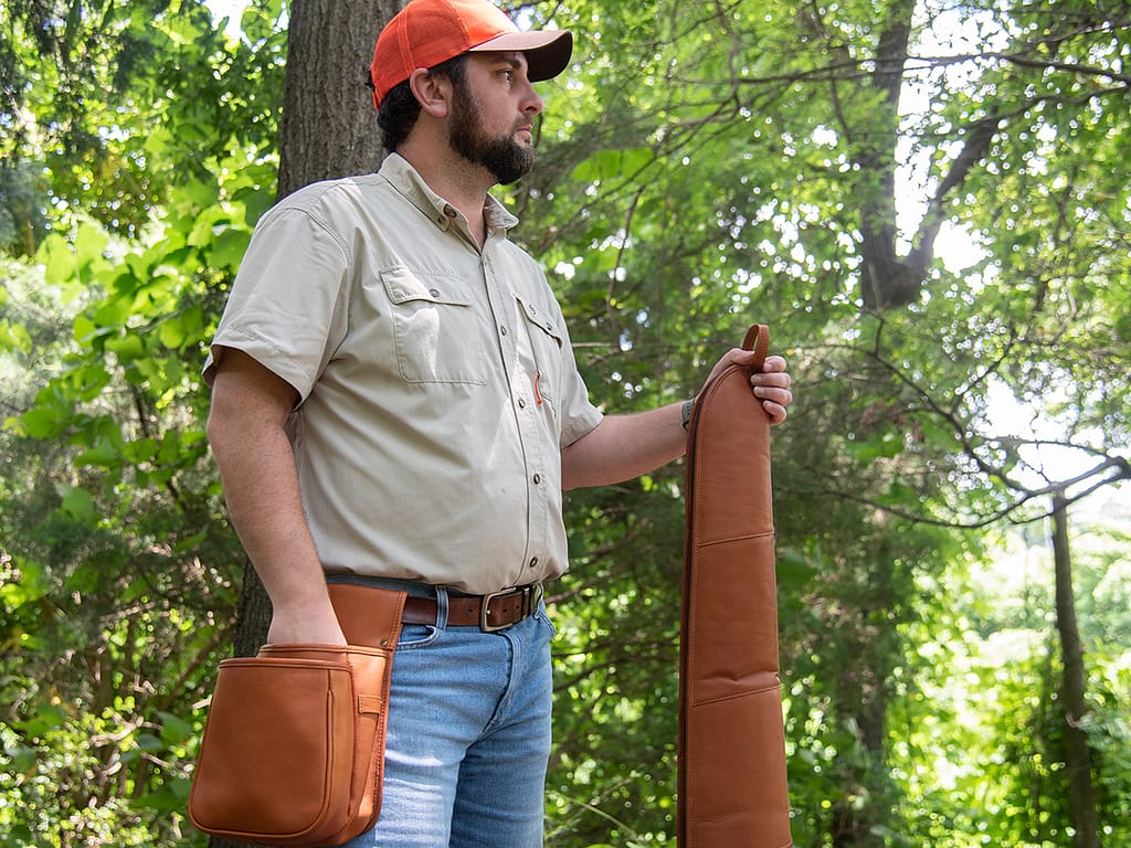 man holding leather ammo case and rifle case
