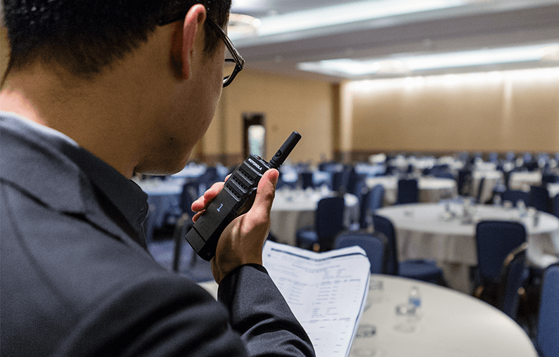 A hotel manager uses a SL300 Motorola Solutions two way radio.